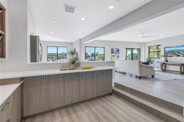 kitchen featuring visible vents, open floor plan, light countertops, freestanding refrigerator, and light wood-style floors