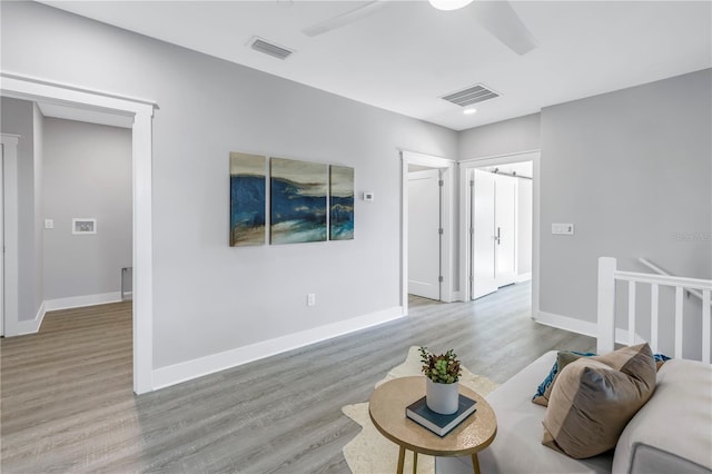 living area with wood finished floors, visible vents, and ceiling fan