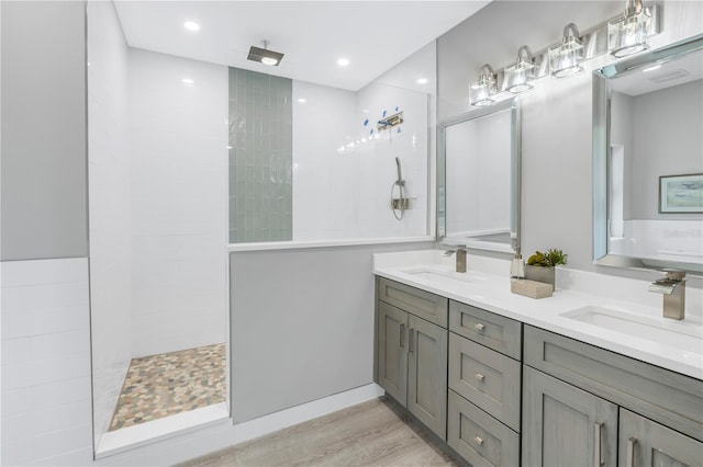 bathroom featuring a sink, double vanity, wood finished floors, and walk in shower