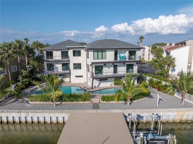 rear view of property featuring stucco siding, a patio, fence, an outdoor pool, and a balcony