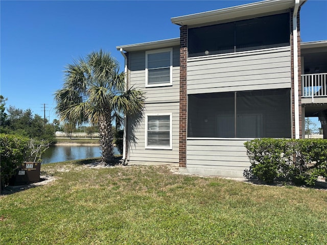 back of property with a yard and a water view