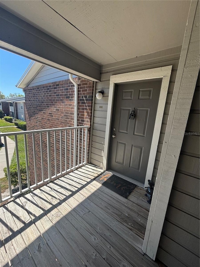 view of exterior entry with brick siding and a balcony