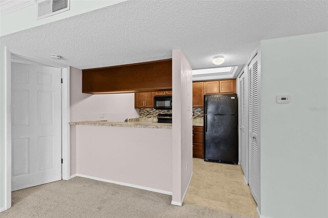 kitchen featuring black appliances, light countertops, light colored carpet, brown cabinets, and backsplash