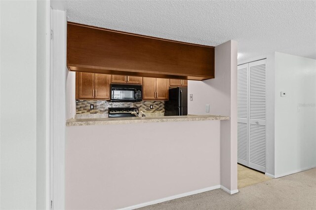 kitchen with baseboards, a peninsula, decorative backsplash, black appliances, and light colored carpet