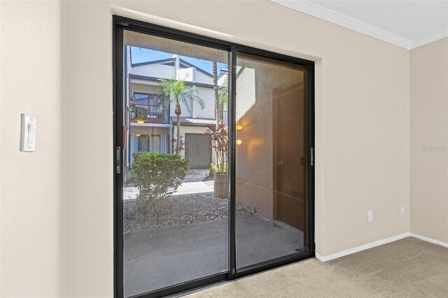 doorway featuring baseboards, ornamental molding, and carpet flooring