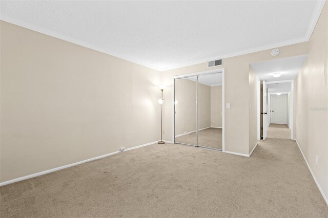 unfurnished bedroom featuring a closet, visible vents, carpet floors, and ornamental molding