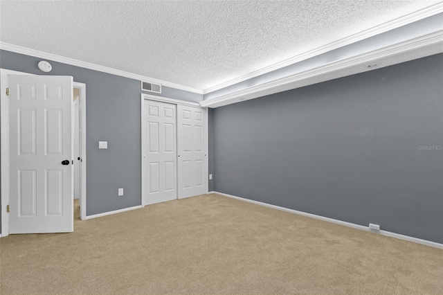 unfurnished bedroom featuring ornamental molding, a textured ceiling, a closet, carpet, and baseboards