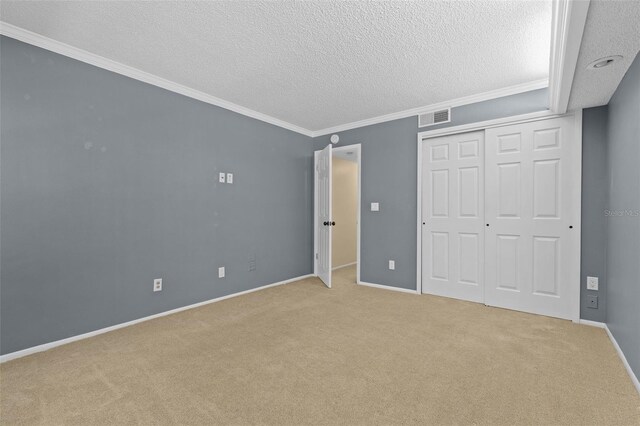 unfurnished bedroom featuring visible vents, baseboards, ornamental molding, carpet flooring, and a textured ceiling