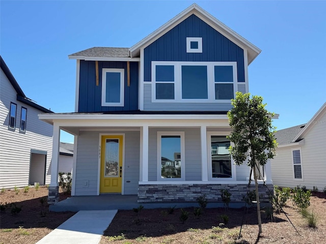 view of front of home featuring stone siding, covered porch, and board and batten siding