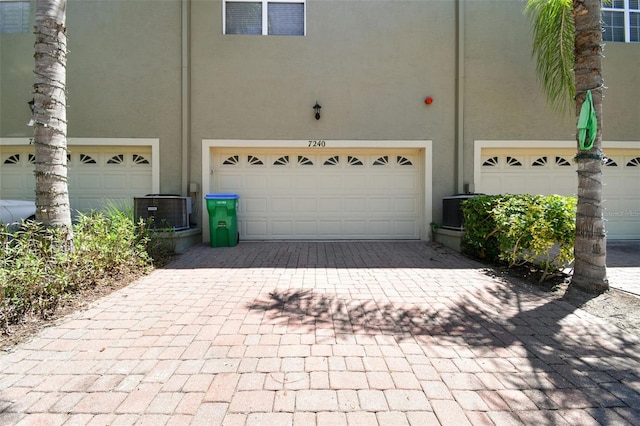 garage with decorative driveway, central AC, and visible vents