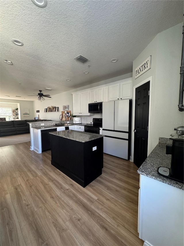 kitchen with a center island, a sink, black appliances, and wood finished floors