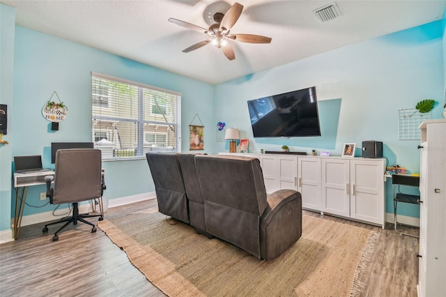 living room with light wood-type flooring, visible vents, baseboards, and ceiling fan