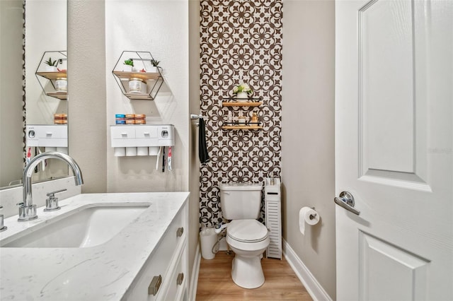 half bath with baseboards, toilet, wood finished floors, and vanity