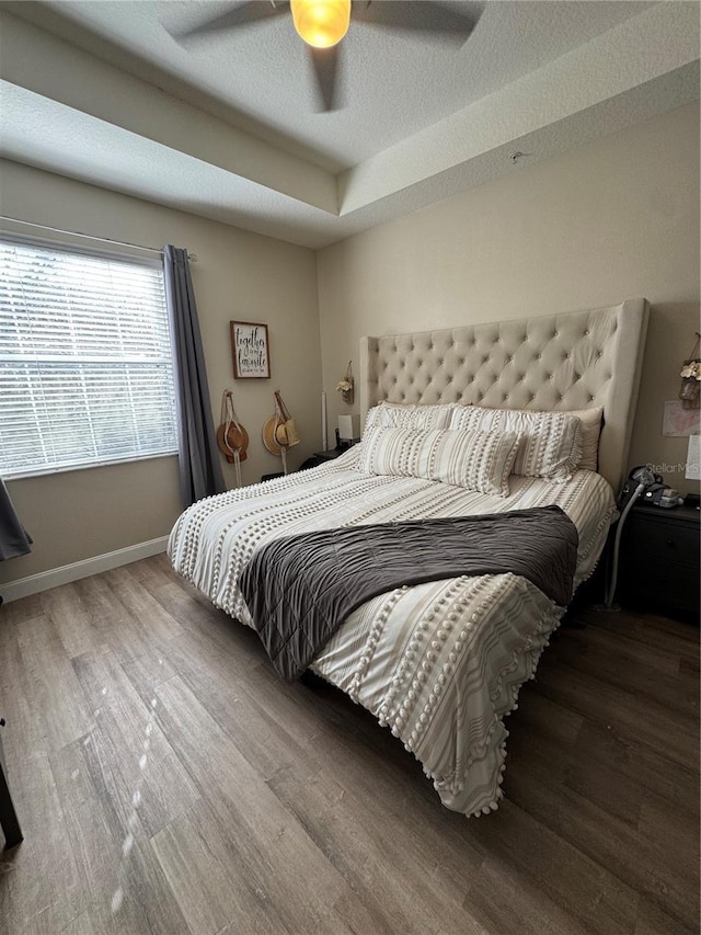 bedroom featuring ceiling fan, baseboards, a textured ceiling, and wood finished floors