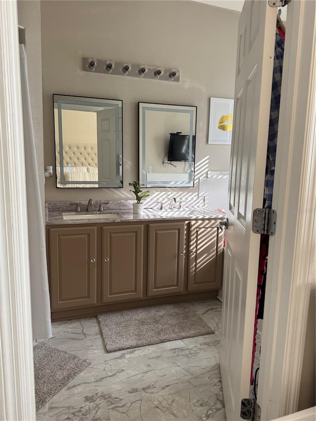 bathroom with double vanity, marble finish floor, and a sink