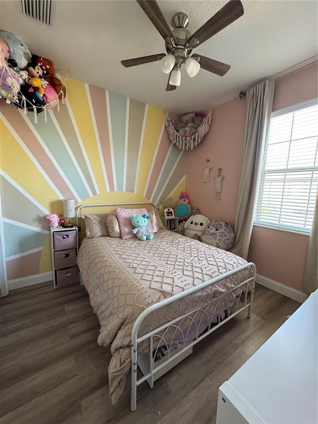 bedroom with ceiling fan, wood finished floors, visible vents, and baseboards