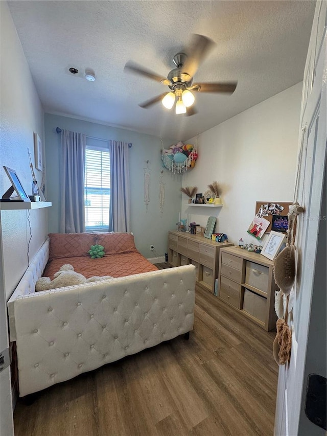 bedroom with ceiling fan, a textured ceiling, and wood finished floors