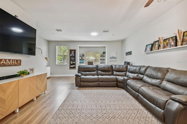 living room featuring visible vents, baseboards, a ceiling fan, and light wood finished floors