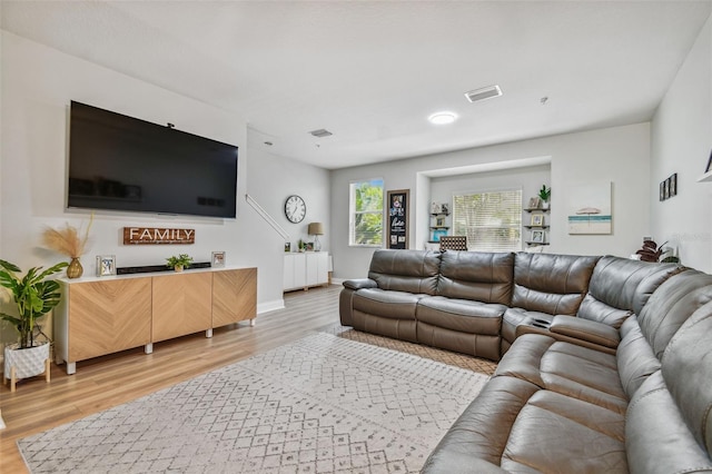 living room with light wood-style floors, visible vents, and baseboards