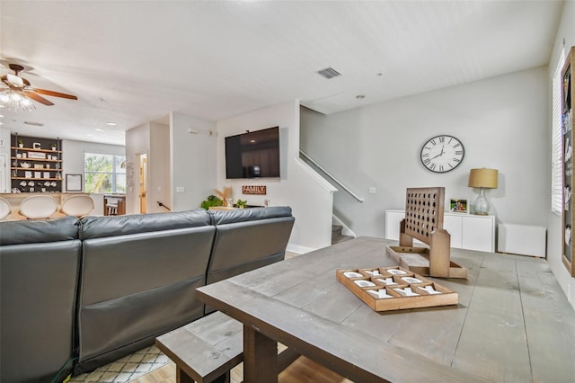 living room featuring visible vents, stairway, and ceiling fan