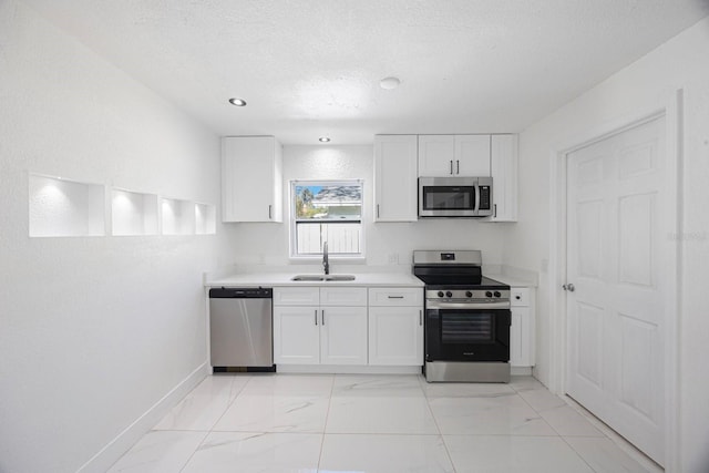 kitchen with a sink, a textured ceiling, white cabinetry, appliances with stainless steel finishes, and light countertops