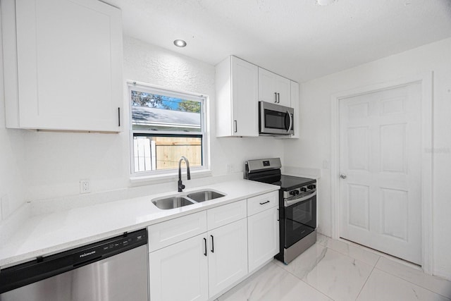 kitchen featuring a sink, light countertops, marble finish floor, and stainless steel appliances