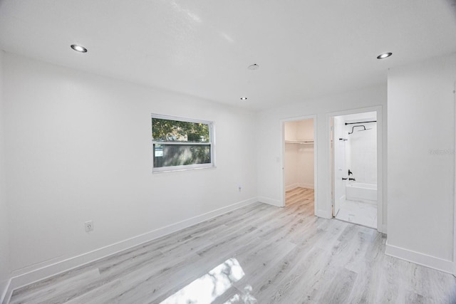 unfurnished bedroom with a walk in closet, recessed lighting, light wood-style floors, and baseboards