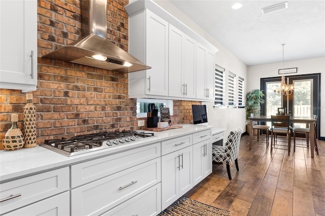 kitchen with dark wood-style floors, stainless steel gas cooktop, light countertops, wall chimney range hood, and backsplash