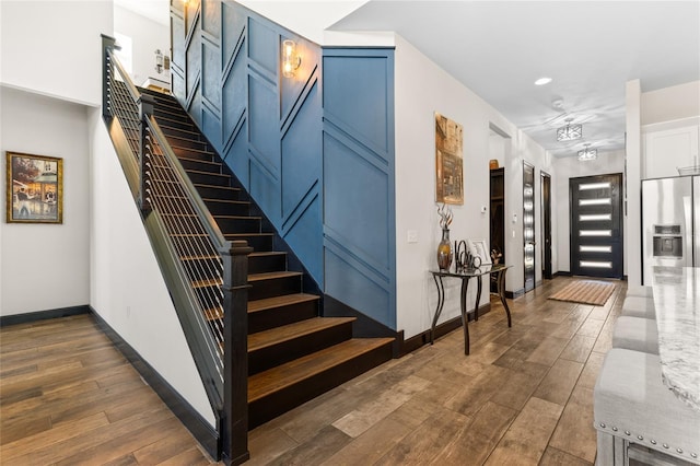 foyer entrance featuring stairway, baseboards, and dark wood-style flooring