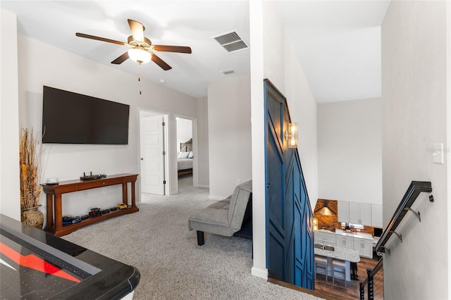 living area with visible vents, carpet floors, and a ceiling fan