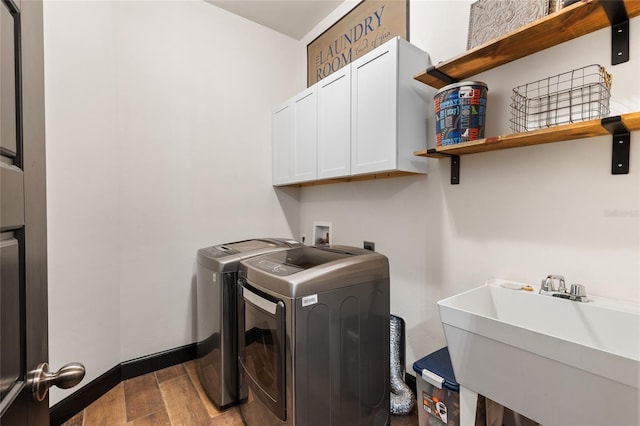 laundry room with washer and dryer, a sink, wood finished floors, cabinet space, and baseboards