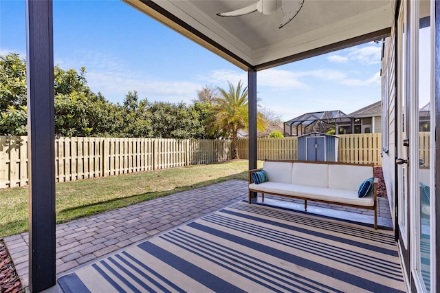 view of patio featuring ceiling fan, a shed, outdoor lounge area, a fenced backyard, and an outbuilding