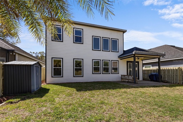 back of property featuring an outbuilding, a lawn, fence, a storage shed, and a patio area