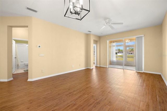 unfurnished room featuring visible vents, ceiling fan with notable chandelier, baseboards, and wood finished floors