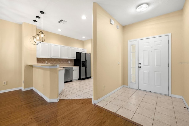 kitchen with visible vents, a peninsula, dishwasher, refrigerator with ice dispenser, and backsplash