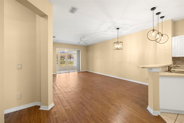 interior space with a sink, visible vents, light wood-style floors, and ceiling fan