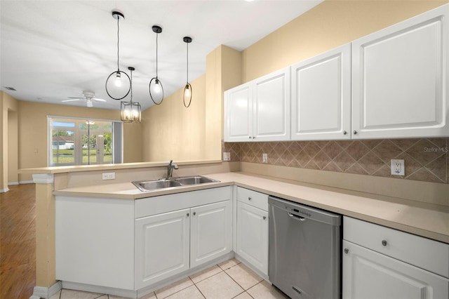 kitchen featuring tasteful backsplash, dishwasher, a peninsula, white cabinets, and a sink