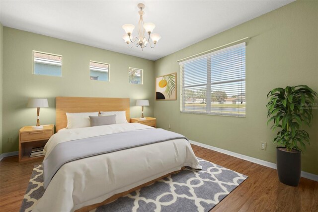 bedroom with wood finished floors, baseboards, and a chandelier