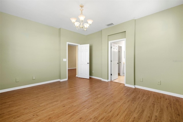 unfurnished bedroom with light wood-type flooring, visible vents, baseboards, and an inviting chandelier