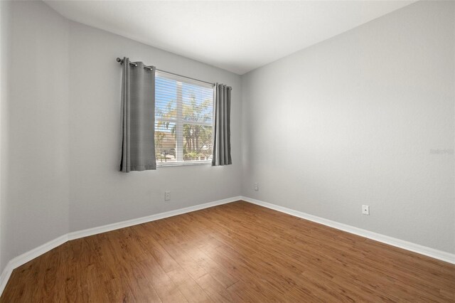 spare room with baseboards and wood finished floors