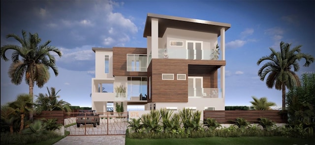 view of front of property with stucco siding, a balcony, and fence