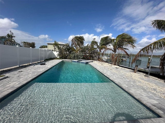 view of pool with a patio, a fenced backyard, a water view, and a pool with connected hot tub