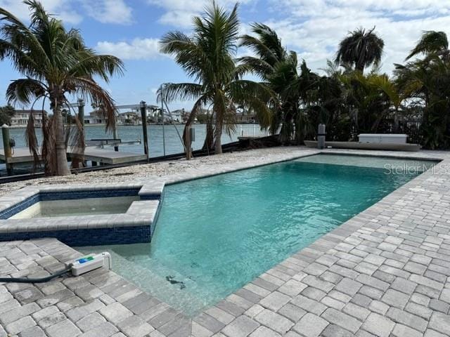 view of swimming pool featuring a patio, a water view, and a pool with connected hot tub