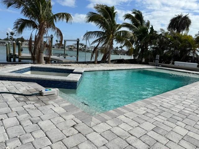 view of swimming pool featuring a patio area, a pool with connected hot tub, a dock, and a water view