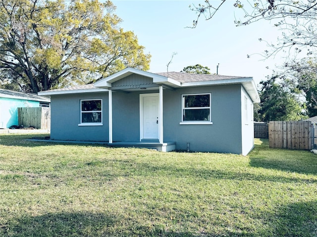 bungalow-style house featuring stucco siding, a front lawn, and fence