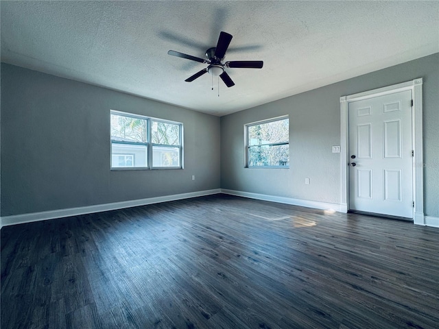 empty room with dark wood-style floors, ceiling fan, a textured ceiling, and baseboards