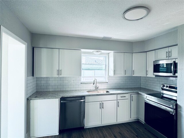 1409 Franklin St, Clearwater, FL 33756 - kitchen with dark wood-type flooring, a sink, stainless steel appliances, white cabinets, and decorative backsplash