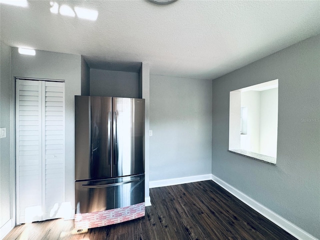 kitchen featuring dark wood finished floors, a textured ceiling, freestanding refrigerator, and baseboards