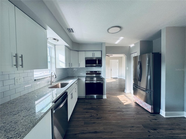 kitchen with visible vents, a sink, stainless steel appliances, white cabinets, and light stone countertops