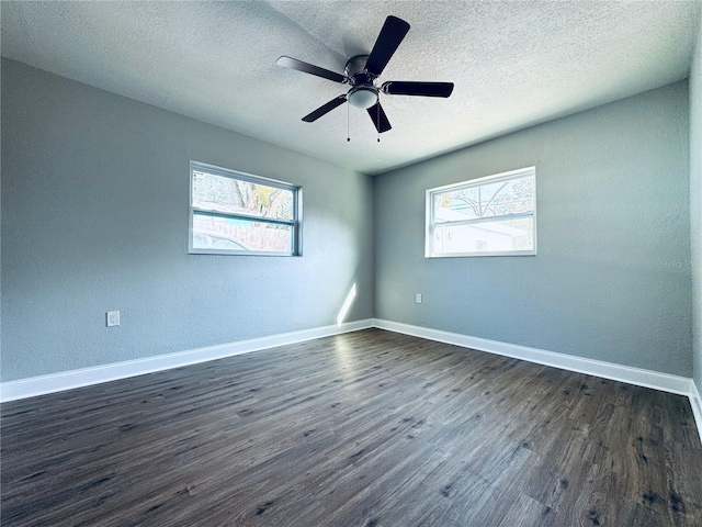 empty room with ceiling fan, baseboards, a healthy amount of sunlight, and dark wood finished floors